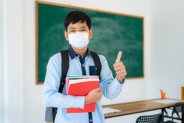 Estudiante de primaria con mochila y libros con una máscara facial