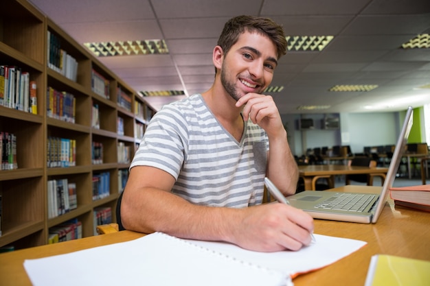 Estudiante que estudia en la biblioteca con la computadora portátil