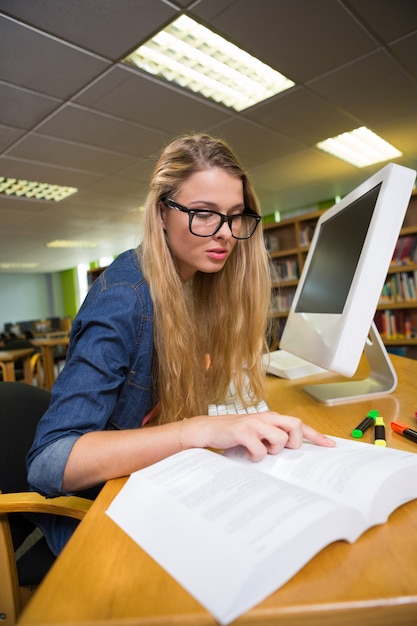 Estudiante que estudia en la biblioteca con la computadora