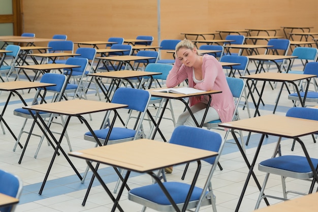 Estudiante que estudia en la sala de examen vacía