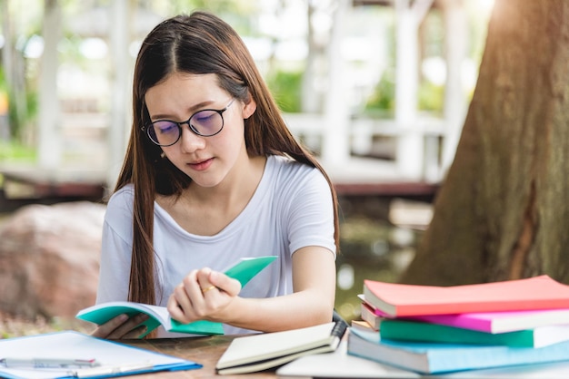 Estudiante que estudia sentada en la mesa al aire libre lee libros