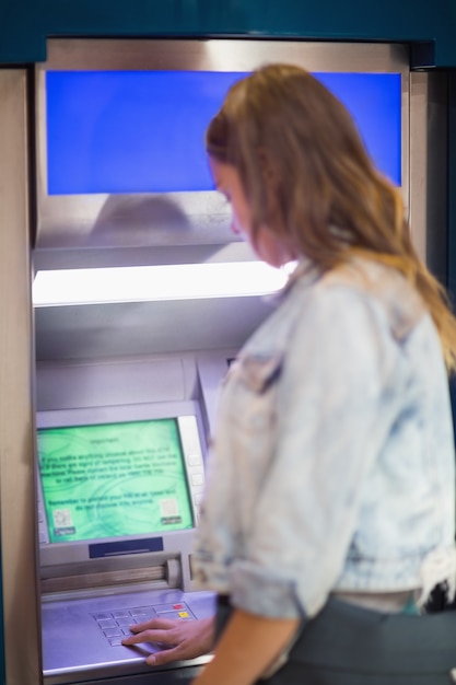 Foto estudiante que ingresa al pin en el cajero automático en la universidad