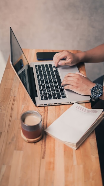 Un estudiante que trabaja en una tarea con su computadora portátil acompañada de una taza de café.