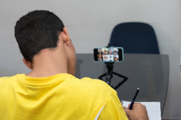 Foto estudiante recibiendo clases virtuales en su teléfono celular