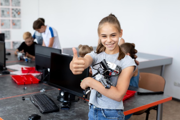 Una estudiante de retrato sostiene un robot en sus brazos que fue ensamblado a partir de piezas de plástico programadas