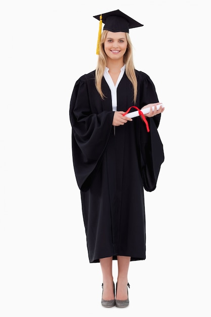 Foto estudiante rubia sonriente en traje graduado sosteniendo su diploma