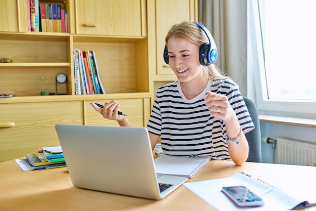 Una estudiante de secundaria adolescente con auriculares haciendo una videoconferencia en una computadora portátil