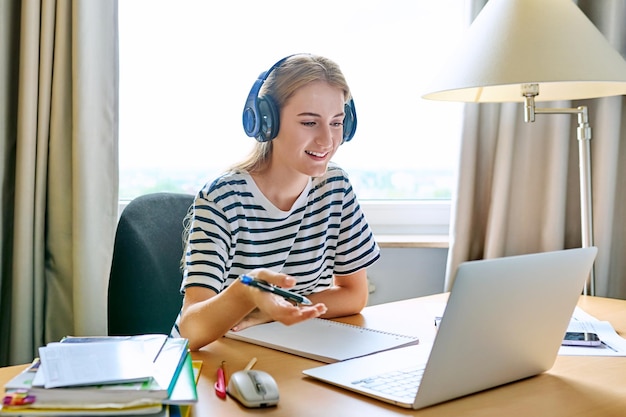 Una estudiante de secundaria adolescente con auriculares haciendo una videoconferencia en una computadora portátil