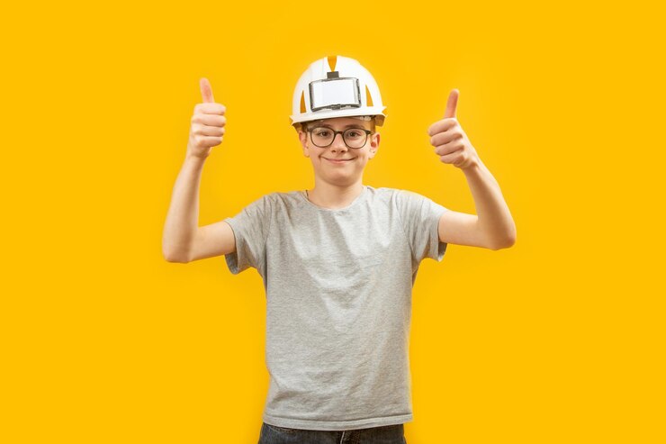 Foto estudiante de secundaria adolescente usa casco protector y muestra los pulgares hacia arriba con dos manos sobre fondo amarillo elección de profesión