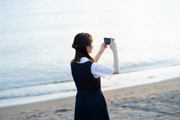 Estudiante de secundaria asiática tomando fotografías de paisajes con un teléfono inteligente