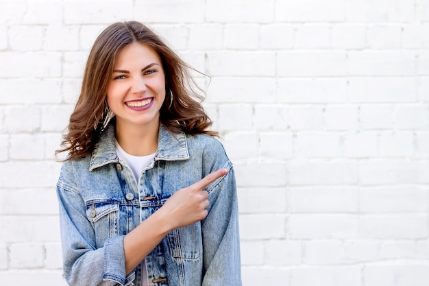 La estudiante señala con un dedo la pared. La muchacha muestra el índice en el fondo