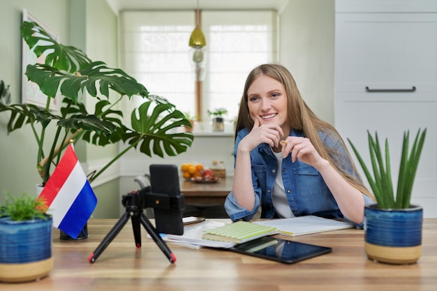 Estudiante sentada en casa estudiando en línea mirando la cámara web del teléfono inteligente