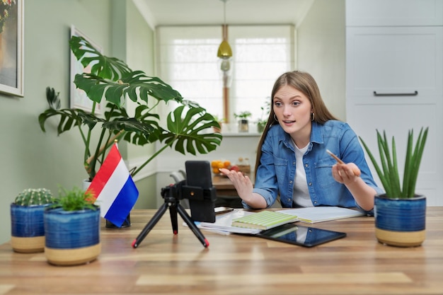 Estudiante sentada en casa estudiando en línea mirando la cámara web del teléfono inteligente