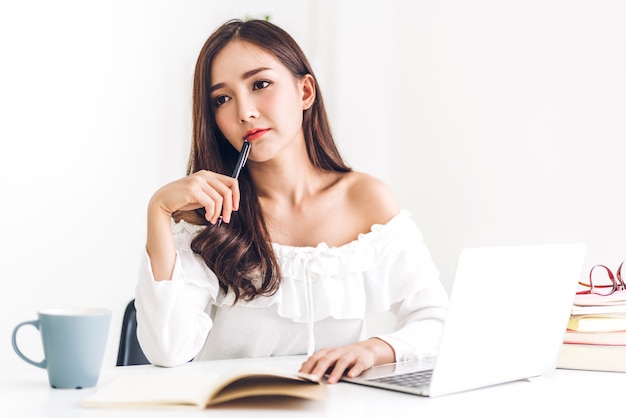 Estudiante sentada y estudiando y aprendiendo en línea con la computadora portátil y leyendo un libro antes del examen en casa. concepto de educacion