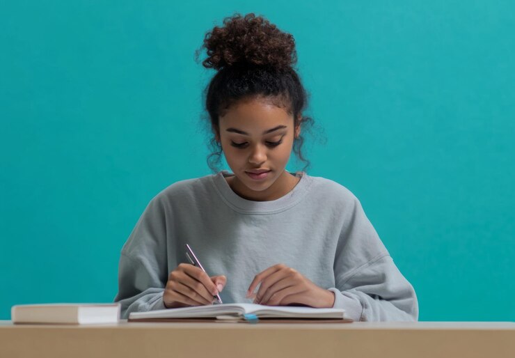 Un estudiante sentado en un escritorio escribiendo en un cuaderno con espacio de copia arriba y abajo