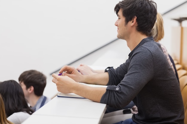 Estudiante sentado en una sala de conferencias y escuchando al maestro