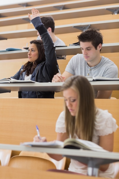 Foto estudiante sentado en la sala de conferencias con la mano hacia arriba
