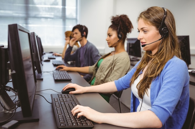 Foto estudiante sentado en la sala de informática usando auriculares