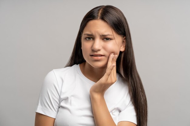 Foto una estudiante se siente incómoda debido a un terrible dolor de dientes. una niña necesita ayuda del dentista.