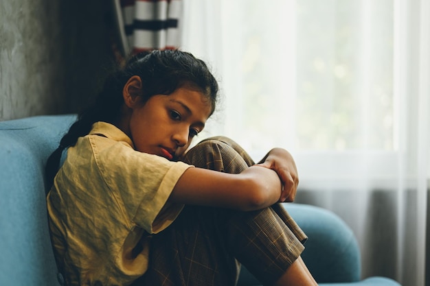 Una estudiante solitaria y triste llorando y abrazándose las rodillas sentada en un rincón Retrato de niño triste e infeliz