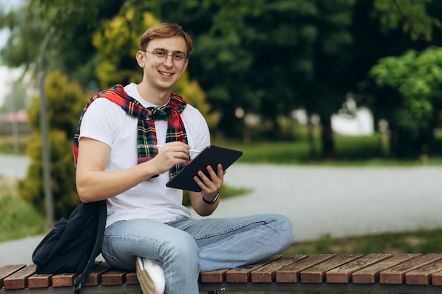 Estudiante sonriente feliz al aire libre con tableta Emoción de alegría El concepto de educación universitaria