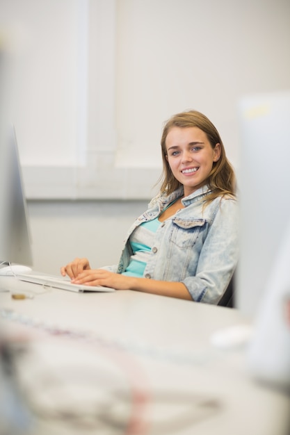 Estudiante sonriente que estudia en la sala de informática