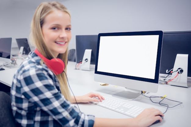 Estudiante sonriente que trabaja en la computadora en la universidad