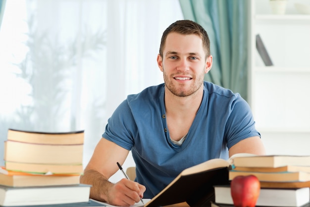 Estudiante sonriente que trabaja en su informe del libro