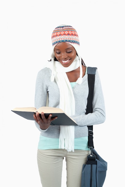 Estudiante sonriente con ropa de invierno leyendo