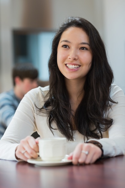 Estudiante sonriente sentado en una cafetería