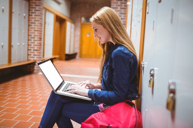 Estudiante sonriente sentado en la computadora en la universidad