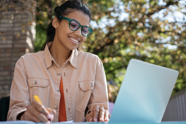 Estudiante sonriente usando una computadora portátil, estudiando en línea, aprendiendo el idioma, preparación de exámenes