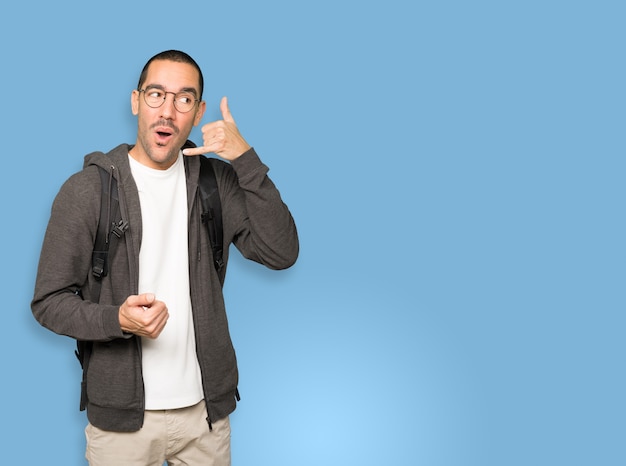 Estudiante sorprendido haciendo un gesto de llamar con la mano