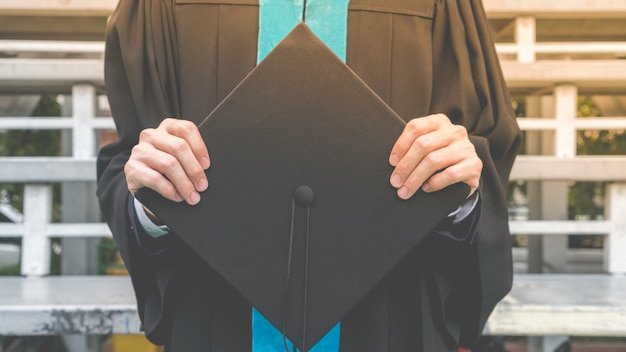 Estudiante sostenga el sombrero en la mano y se gradúa de la universidad.