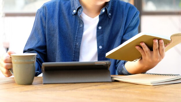 Estudiante sosteniendo el cuaderno y usando tableta digital