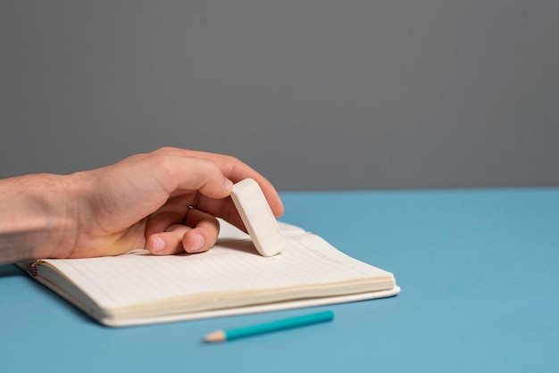 Un estudiante sosteniendo la goma y borrando errores en el cuaderno