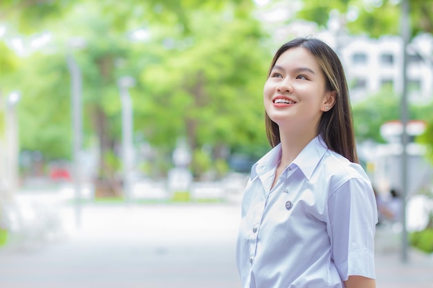 Estudiante tailandés adulto en uniforme de estudiante universitario Chica hermosa asiática de pie sonriendo confianza