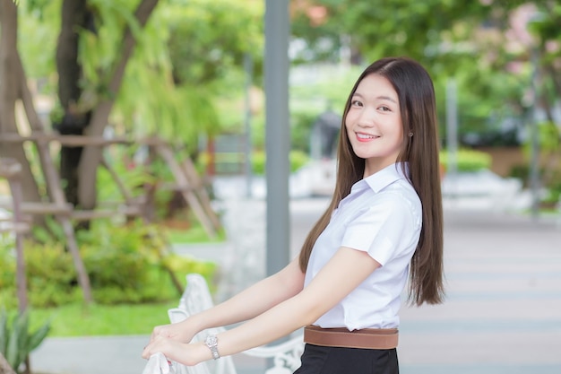 Foto estudiante tailandés en uniforme de estudiante universitario chica hermosa asiática sentada felizmente en la universidad