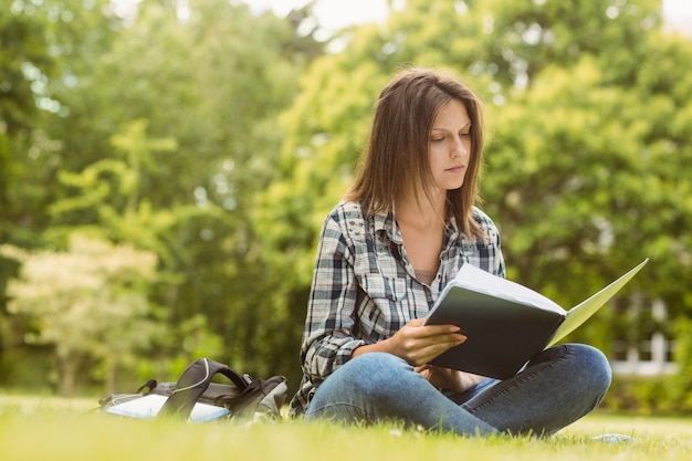 Estudiante de la Universidad sentado leyendo el libro