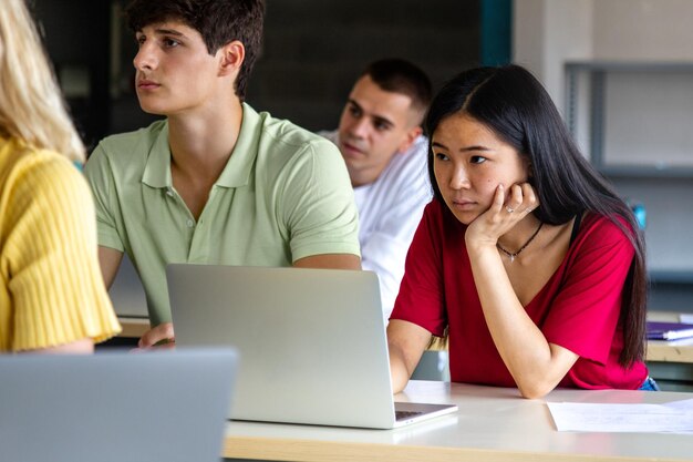 Estudiante universitaria adolescente asiática en clase escuchando una conferencia usando una computadora portátil para tomar notas