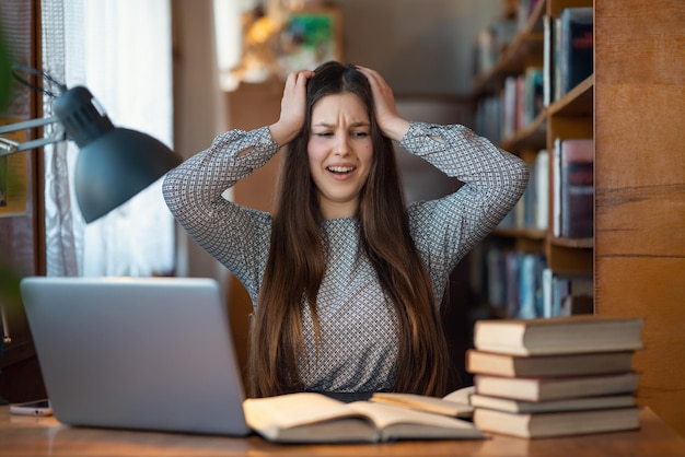 Estudiante universitaria agarra su cabeza sorprendida por la cantidad de tareas que tiene que hacer Educación difícil en concepto de exámenes de plazos universitarios