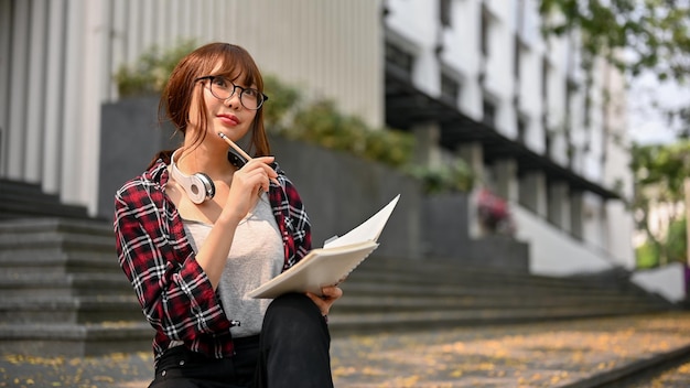 Estudiante universitaria asiática inteligente e inspirada pensando en algunas ideas para su proyecto escolar