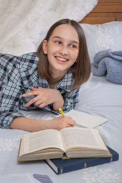 Estudiante universitaria se encuentra en la cama, disfruta del tiempo libre en el dormitorio.