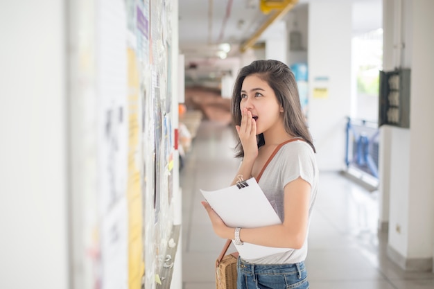 Una estudiante universitaria es emocionante con el informe del examen