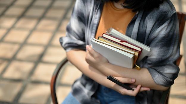 Una estudiante universitaria con ropa informal sentada al aire libre con sus libros