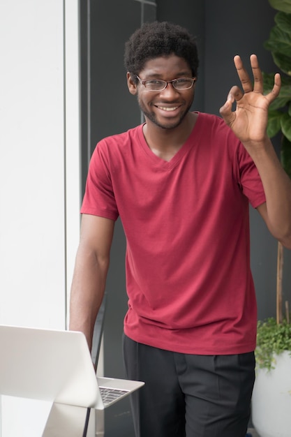 Estudiante universitario feliz que señala la muestra aceptable de la mano; retrato de hombre nerd sonriente feliz, estudiante universitario apuntando bien, gesto de la mano bien, sí, aceptación, buen concepto de educación; Modelo de hombre adulto joven africano