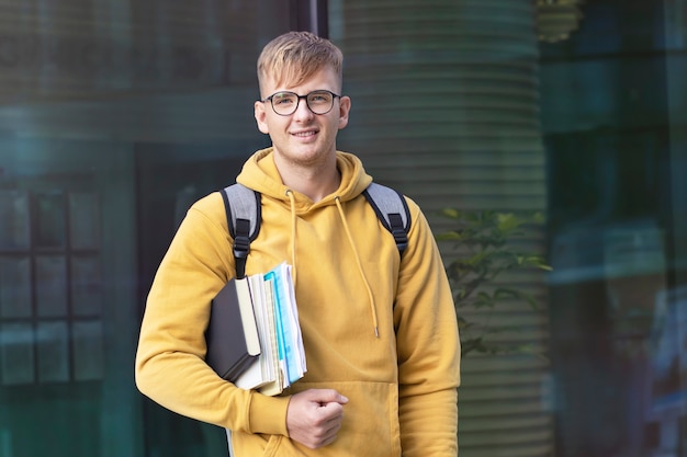 Estudiante universitario feliz en vasos con libros y mochilas