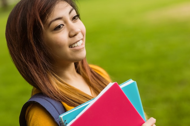 Estudiante universitario femenino con libros en el parque