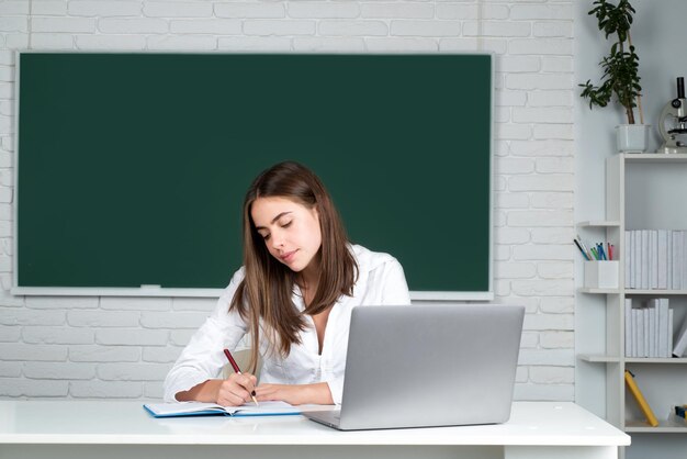 Estudiante universitario femenino que trabaja en una computadora portátil en el aula preparándose para un examen