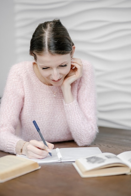 Estudiante universitario hermoso feliz se sienta en el piso, leyendo un libro